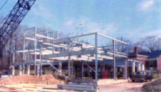 bedford (2) Steel framework of a building under construction with a crane and construction materials on site.