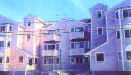 courtyard (1) Three-story apartment building with multiple balconies, stair entrance, and visible power lines in front.
