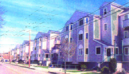 courtyard (2) Row of modern, multi-story townhouses along a residential street under a blue sky.