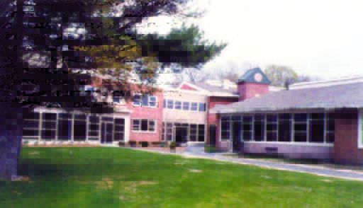 maria (2) A two-story brick building with large windows, a clock tower, and a grassy lawn in front.