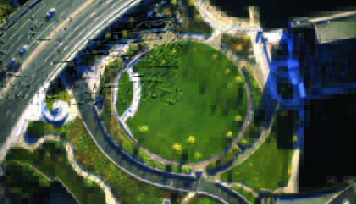 revere (2) Aerial view of a circular green lawn surrounded by pathways and landscaping near a road.