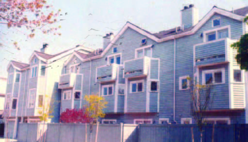 rollins (2) Row of light blue multi-story townhouses with small balconies and a wooden fence in the foreground.