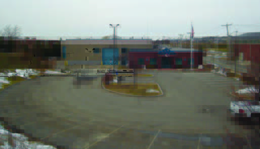 winthrop (1) A nearly empty parking lot in front of a building on a cloudy day, with patches of snow on the ground.